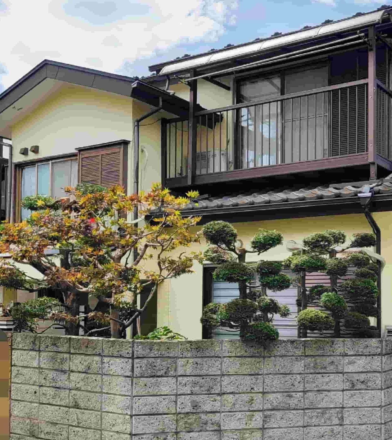 剪定後、丸く刈り込まれた植木が整い外観がすっきりした同じ邸宅